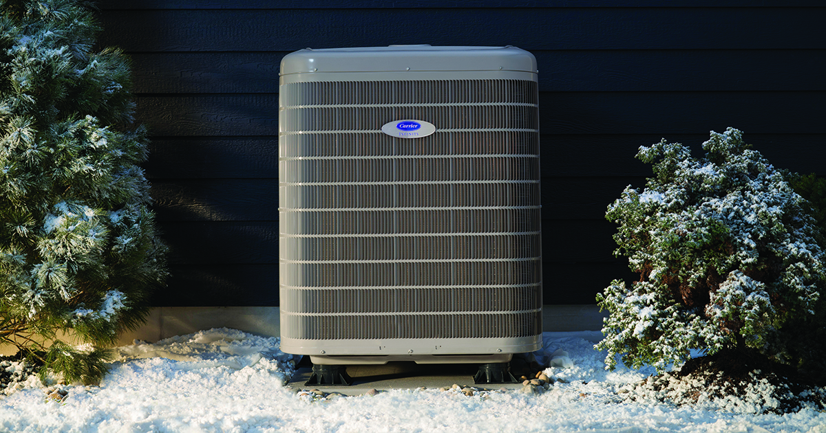 a carrier cold climate heat pump in cold weather sits outside in the snow