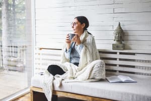 peaceful-woman-sitting-on-bench-outdoors-with-mug-3x2