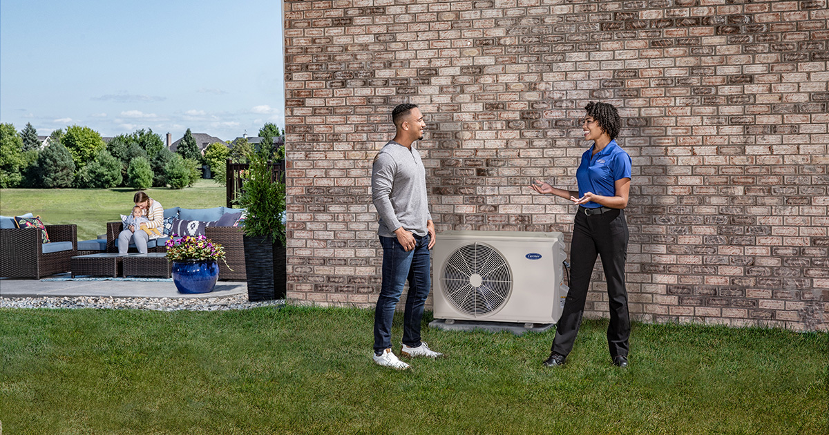 A Carrier dealer speaking to a homeowner outside next to a heat pump mini split