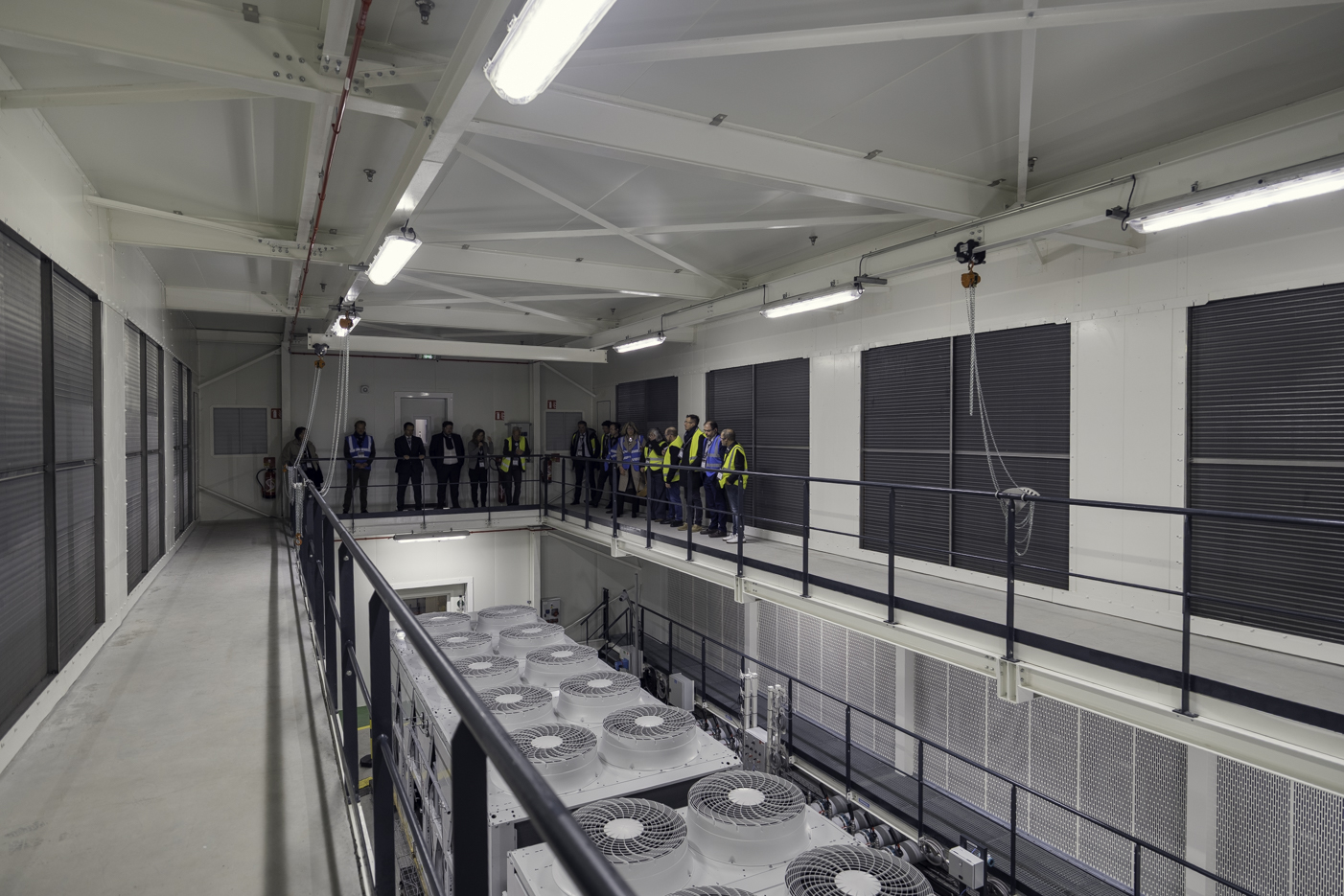 Inside Carrier’s new testing facility in Montluel, France Interior view of Carrier’s new testing facility in Montluel, France, with visitors on an elevated walkway above large HVAC test equipment