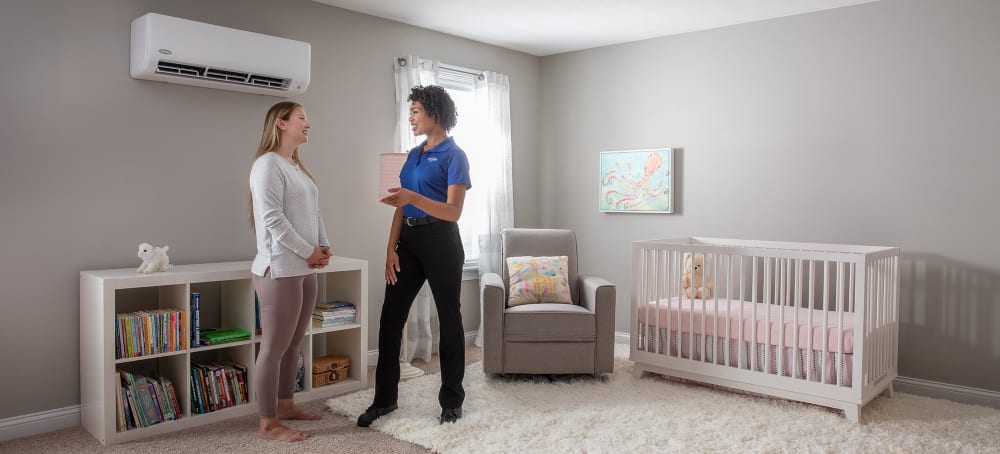 A Carrier expert discussing mini split hvac pros and cons with a homeowner in a baby nursery.