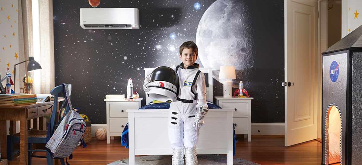 a boy in a spaced themed bedroom with a ductless air conditioner unit installed