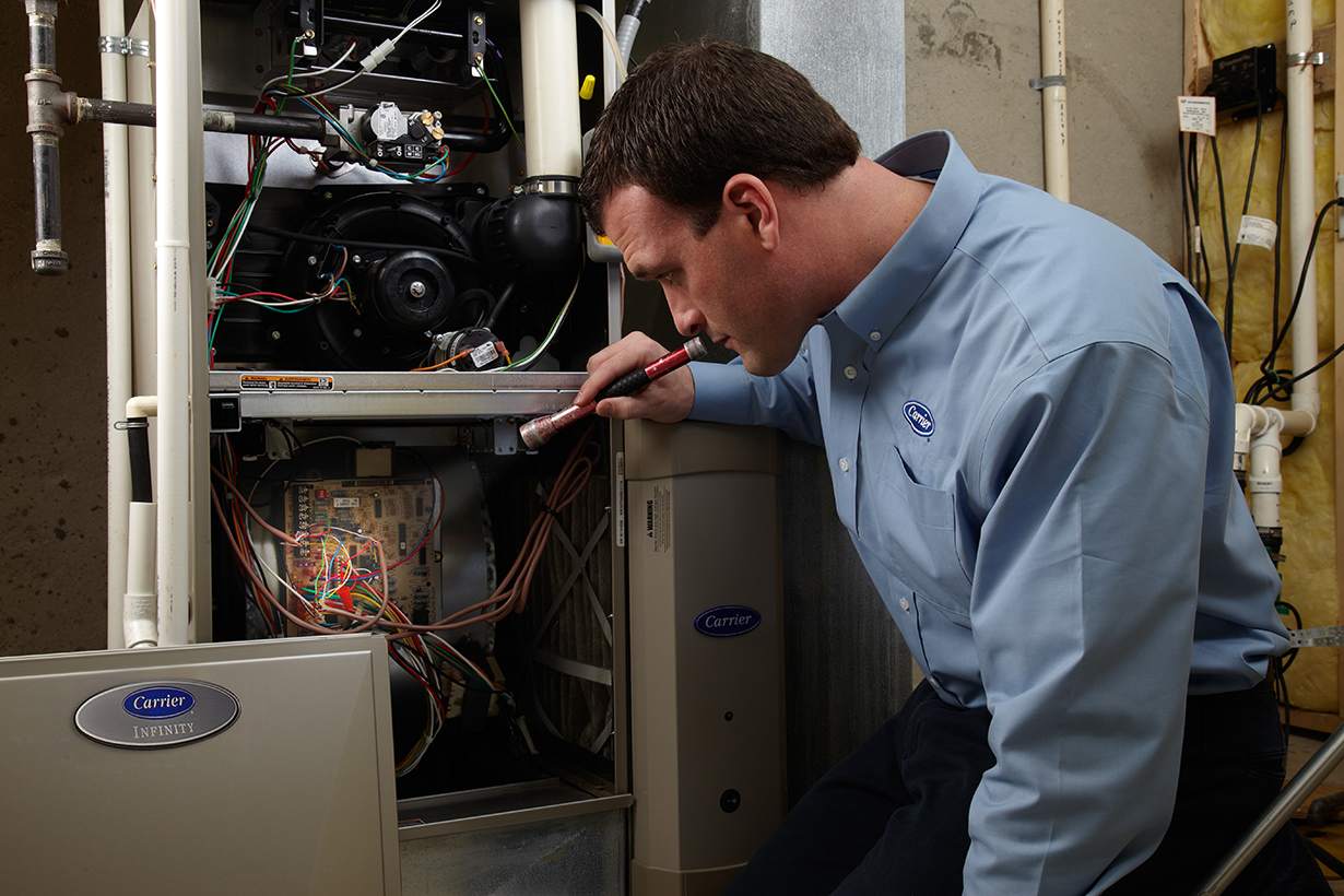 a carrier dealer with a flashlight exploring the cost of furnace repair