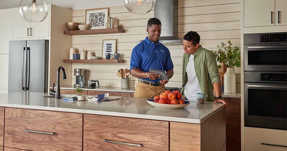 A Carrier expert explaining to a man in his kitchen how to choose the best multi zone mini split for his home.