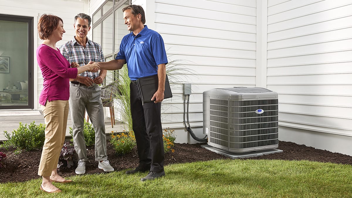 a homeowner shakes the hand of a carrier dealer after heat pump repair is performed