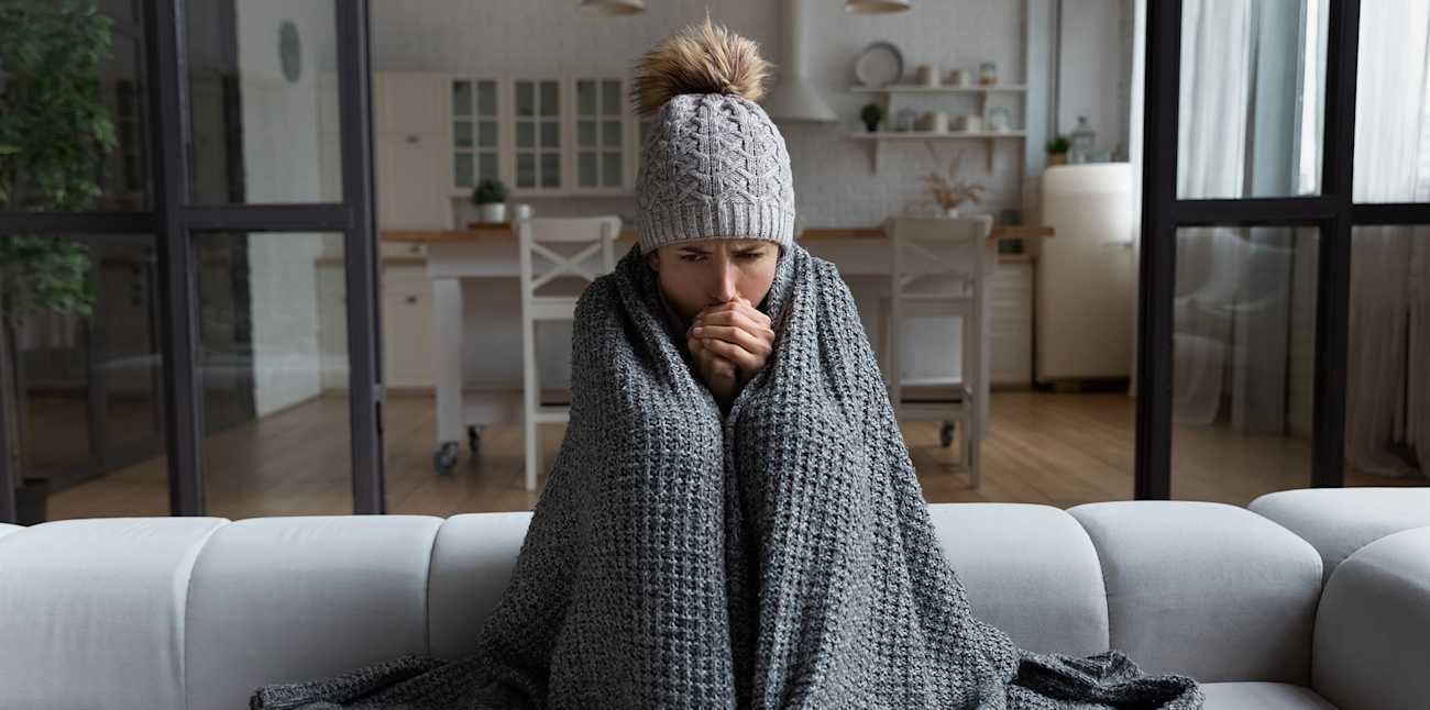 a woman shivers inside due to furnace not blowing hot air