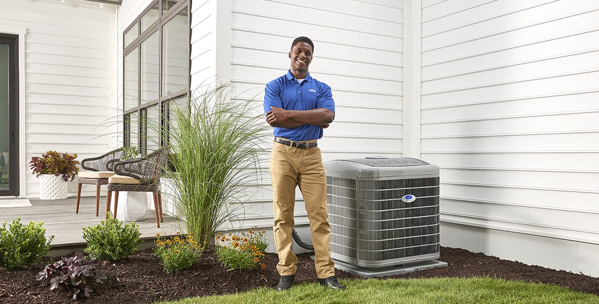 a carrier dealer stands by split ac unit outside home