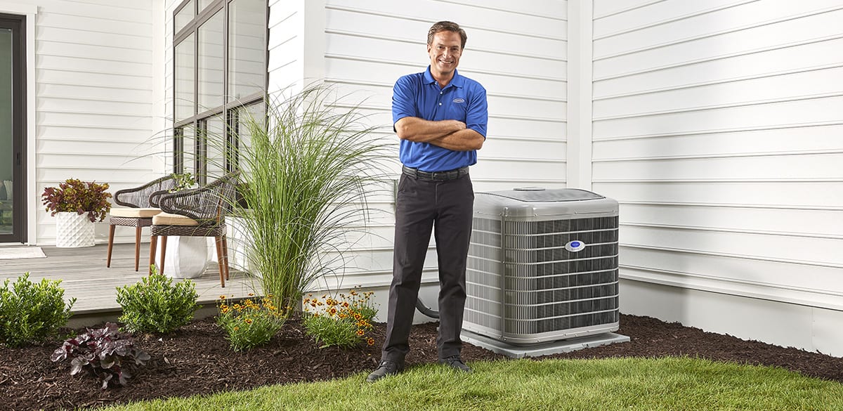 a carrier dealer stands next to an installed heat pump system
