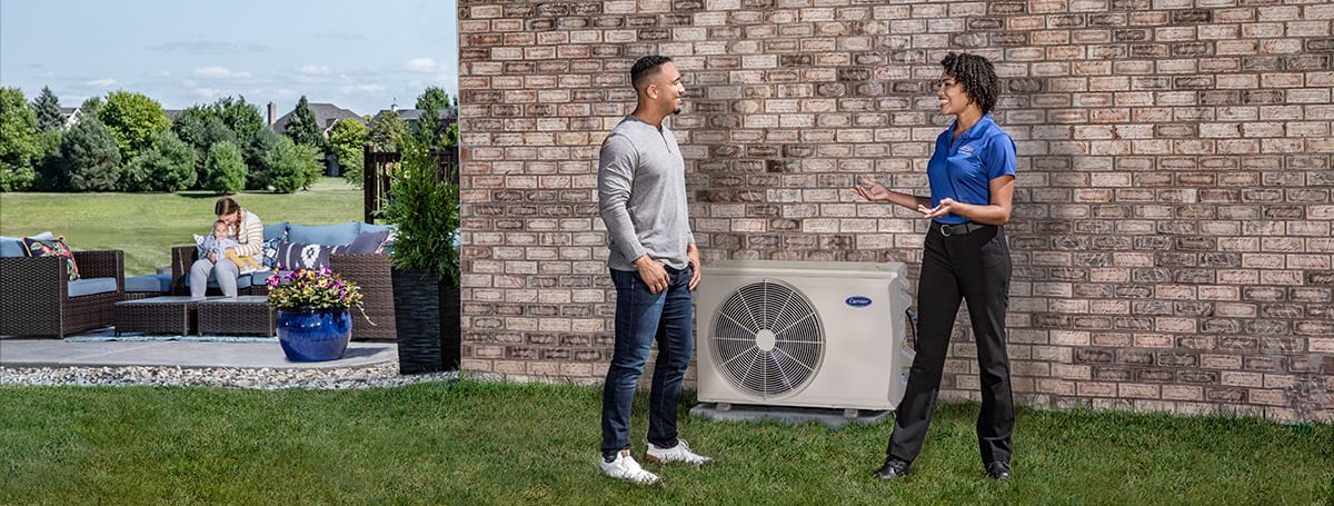 a carrier dealer explains heating and cooling hvac system options to a homeowner outside