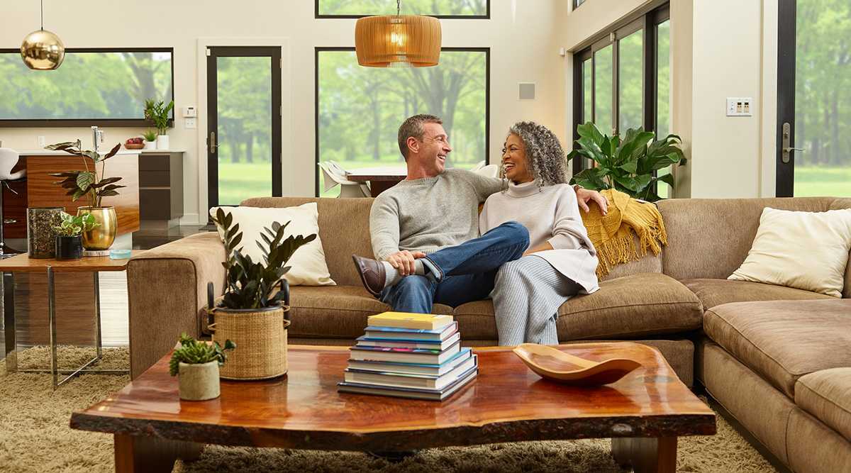 a couple relaxes in living room after air conditioning and heating system is installed