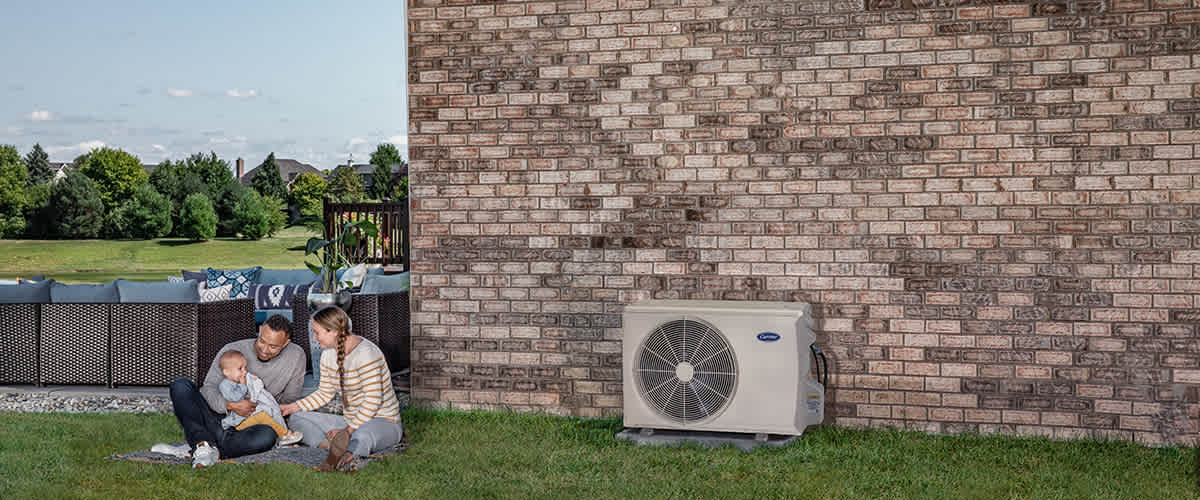 a family relaxes outside next to mini split air conditioner