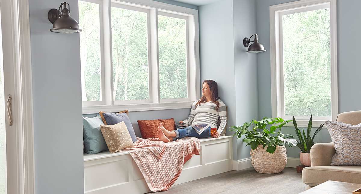 a woman relaxes inside home after ac compressor unit replacement