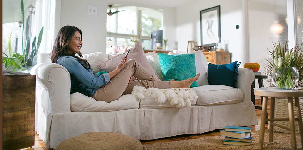 a woman relaxes on couch after heat and air conditioning unit is installed