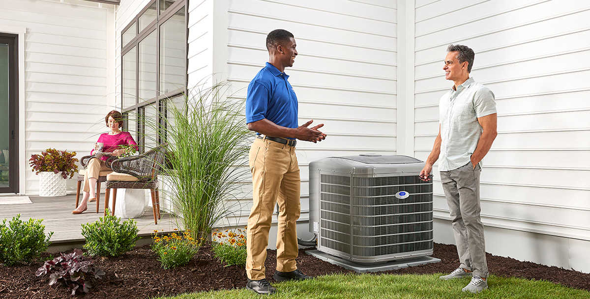 a technician from carrier ac company discusses air conditioner and ac unit options with a homeowner outside
