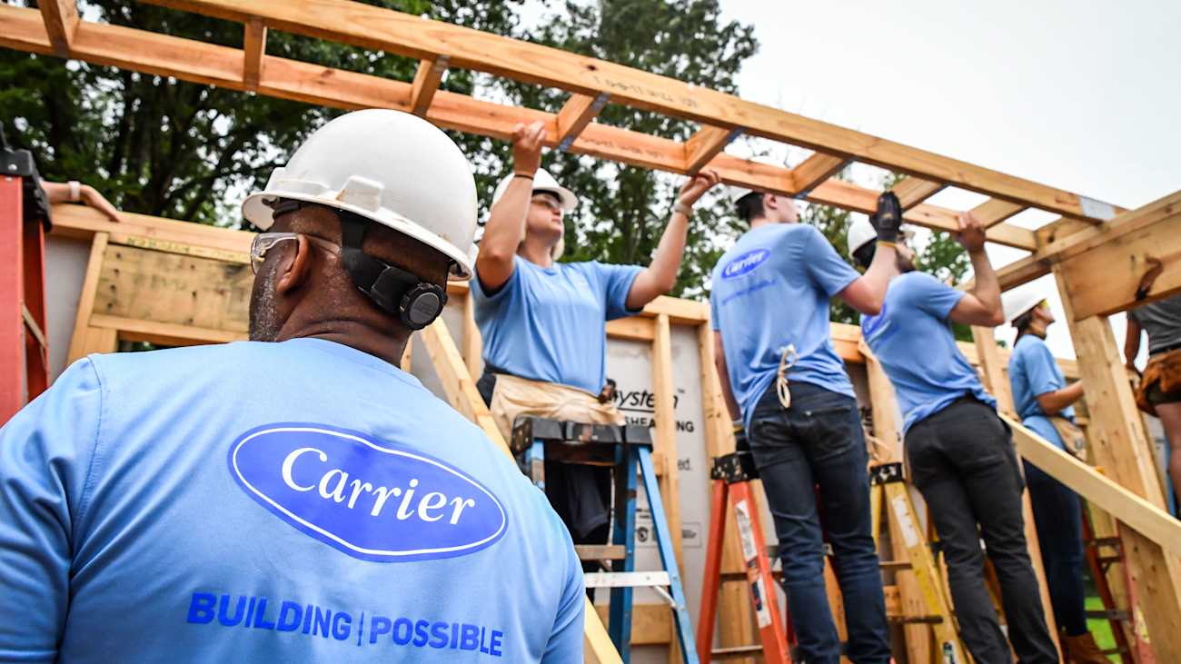 Construction workers wearing t-shirts with the Carrier logo while working on a building site