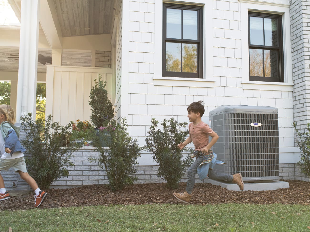 boys-running-by-carrier-heat-pump