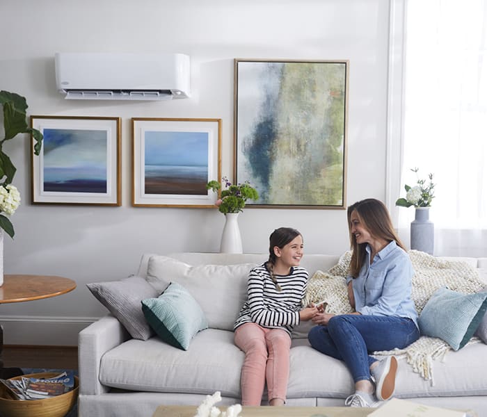 a-mother-and-daughter-enjoy-the-cool-air-from-their-ductless-mini-split-ac-unit