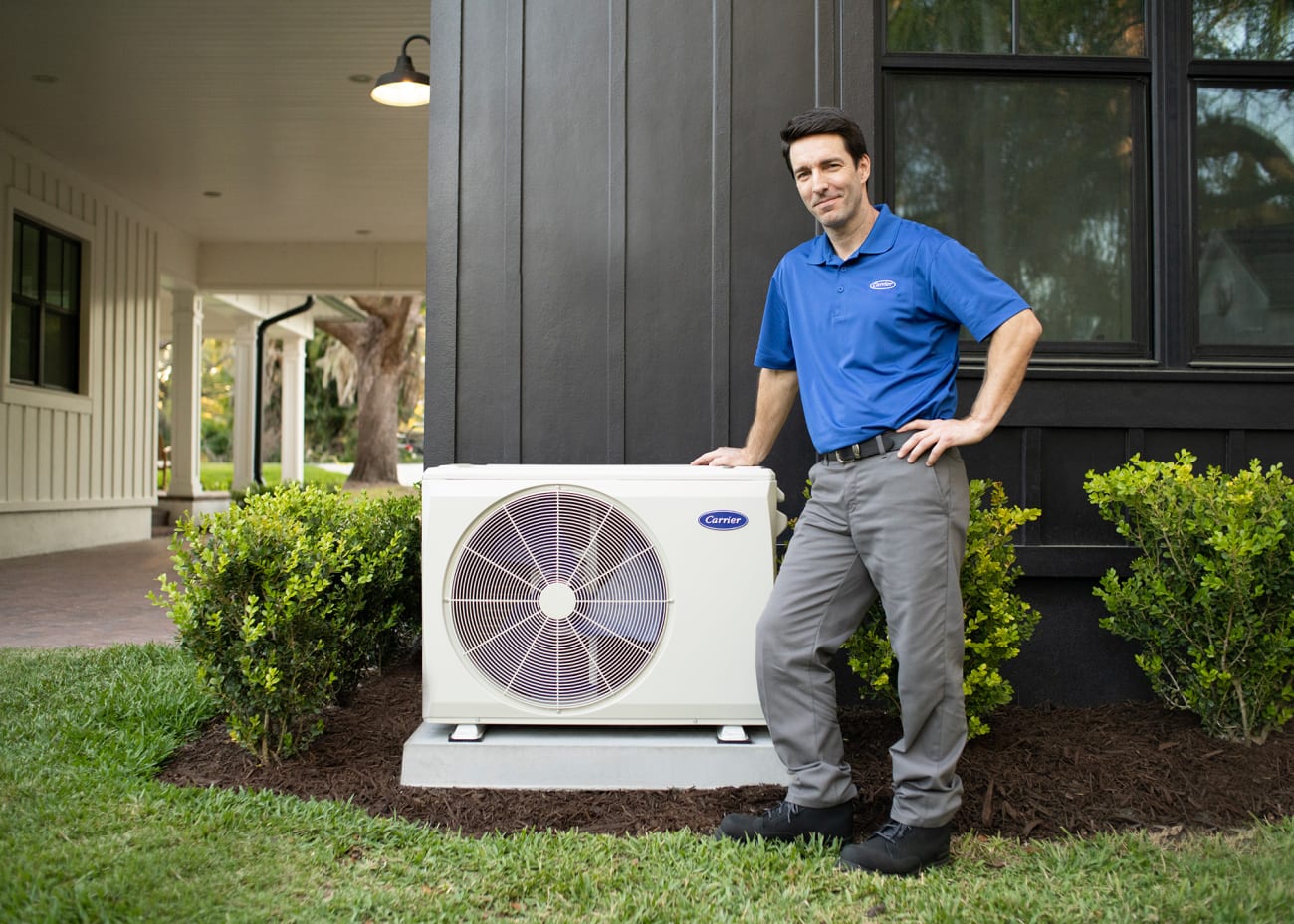 a carrier dealer stands next to a carrier ductless mini split outdoor unit