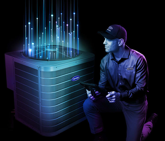 a carrier technician kneels by an air conditioner with intelisense technology
