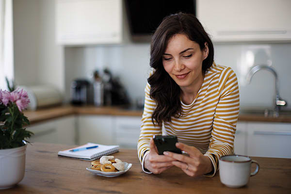 woman-in-a-kitchen-reading-about-the-carrier-smartsave-program-on-her-phone