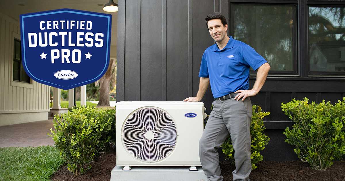 carrier-certified-ductless-pro-standing-next-to-a-heat-pump-with-program-logo