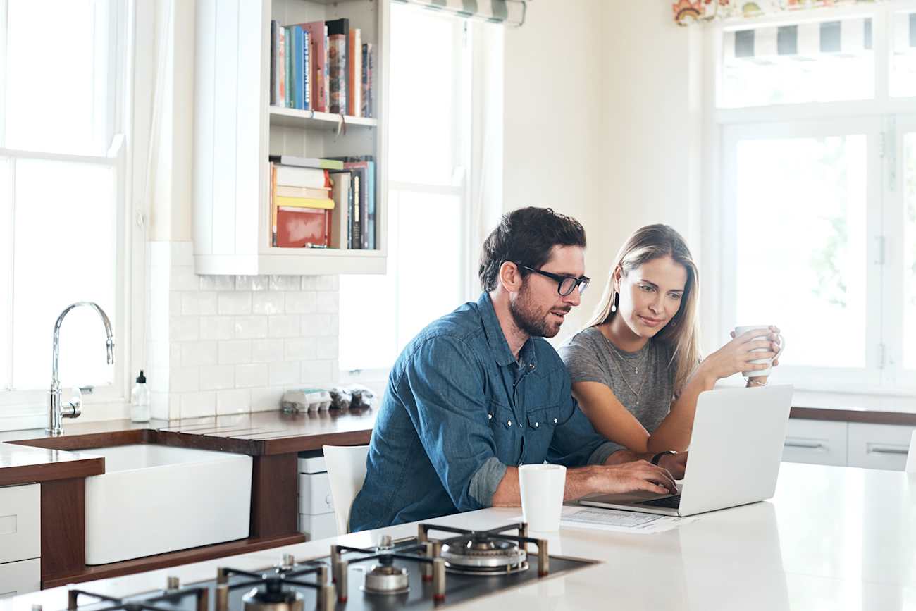 husband and wife in kitchen registering their heating and cooling unit online