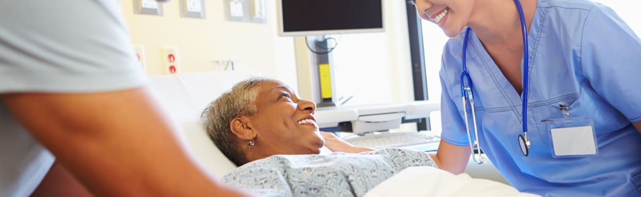 carrier-nurse-talking-to-woman-in-hospital-bed