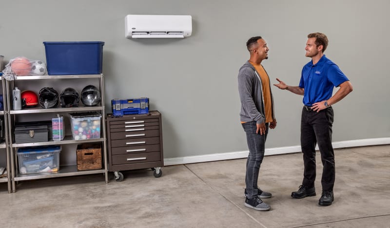 A Carrier dealer in garage talking to man after mini split installation.
