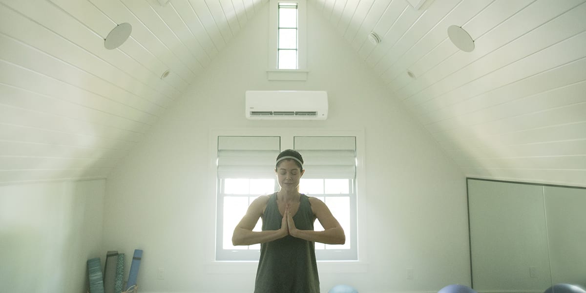 woman-doing-yoga-in-a-white-room-with-2-zone-ductless-mini-split-installed