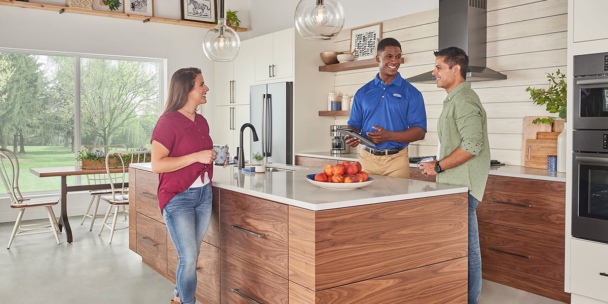 carrier-dealer-discusses-the-cost-to-replace-an-oil-furnace-with-homeowners-in-kitchen