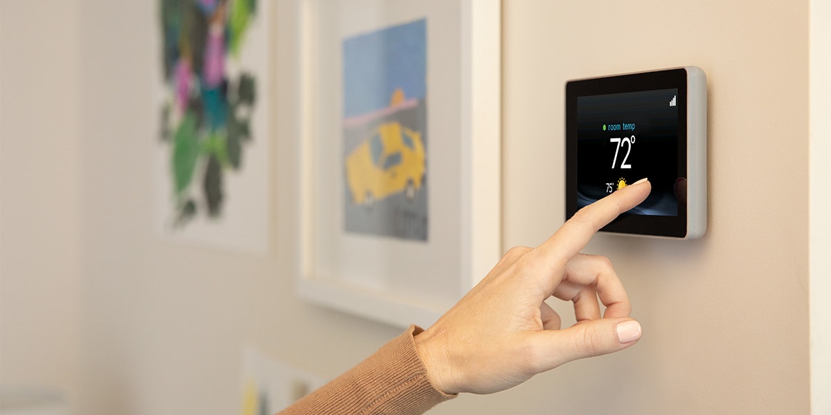 woman-changing-the-temperature-on-her-thermostat