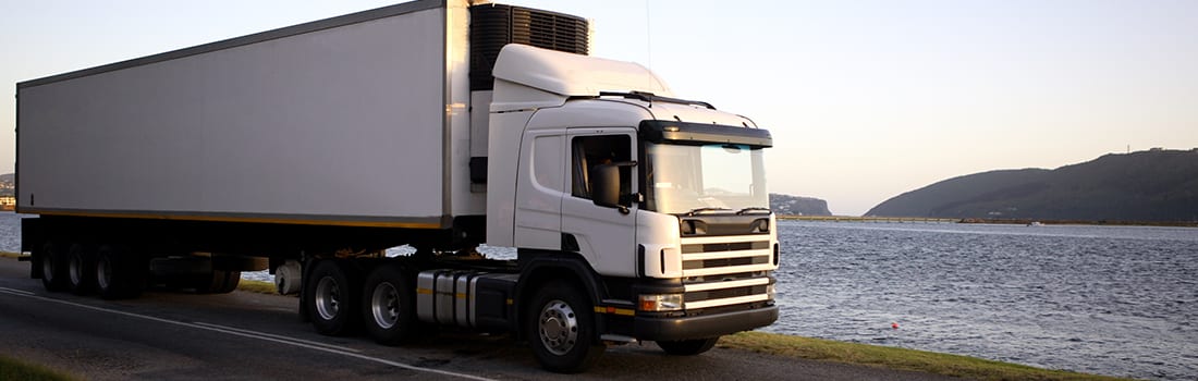 Monitor Placement blog header Refrigerated tractor trailer on road next to lake