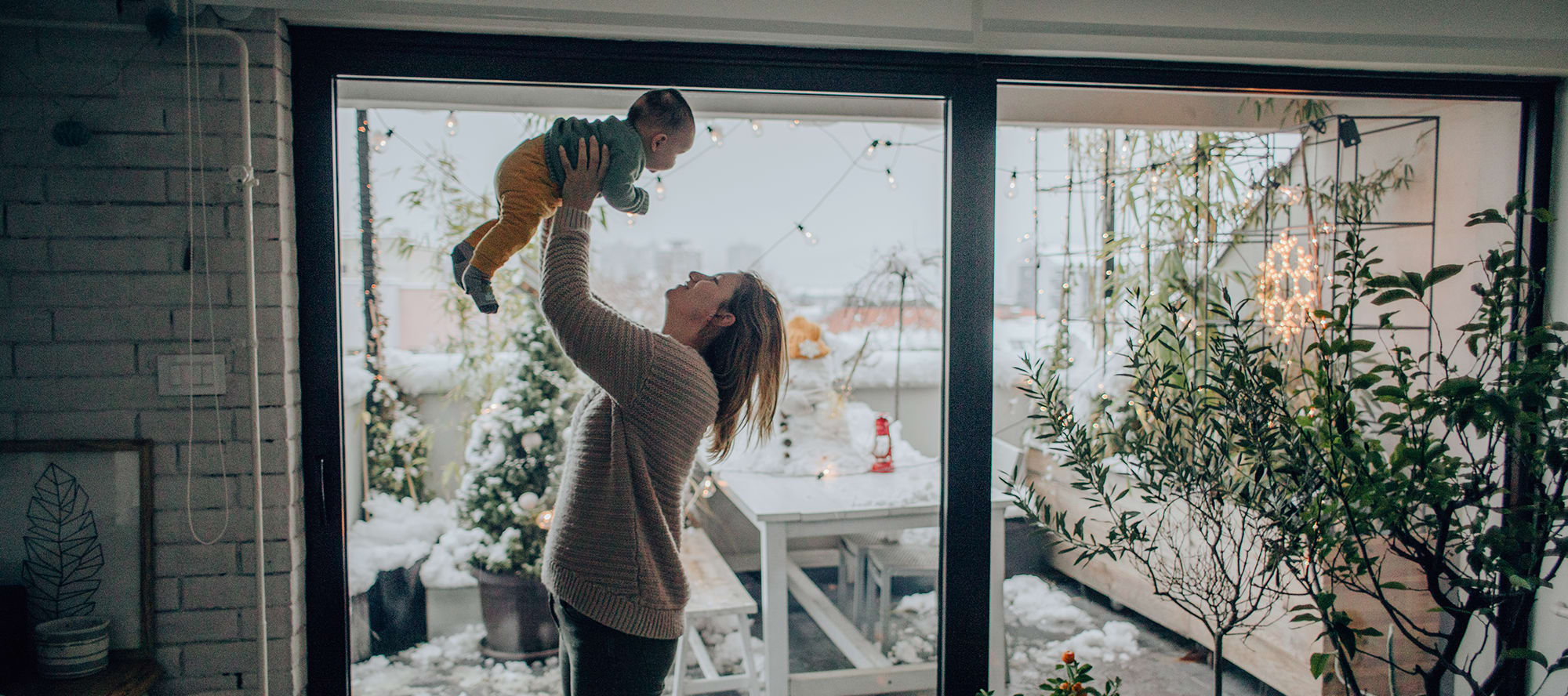 mom-and-baby-in-arms-in-front-of-window a mom and baby in front of window of home with whole house humidifier installed