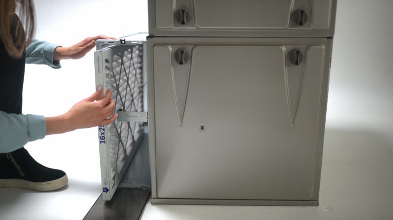 a homeowner shows how to change a furnace filter after learning how often should you change your furnace filter