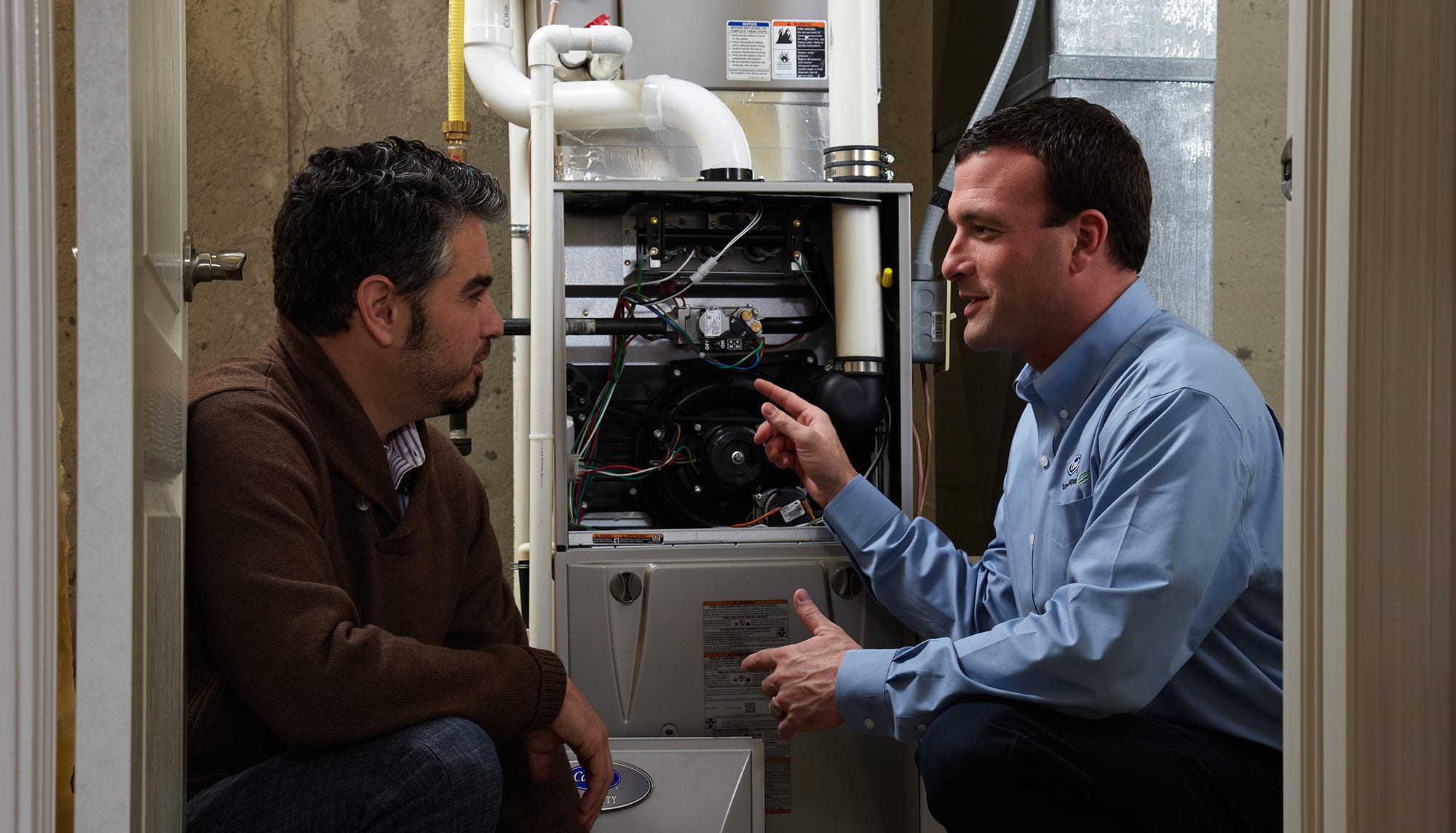 a carrier technician and man discuss factors in buying a furnace