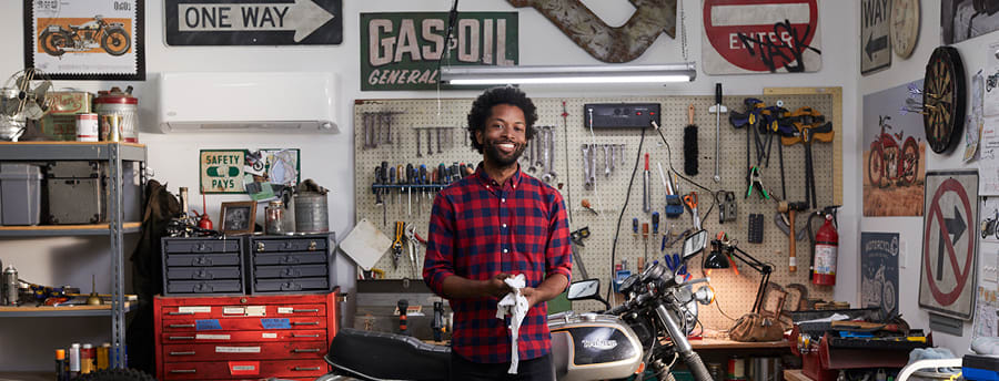most-efficient-mini-split a man smiling in a garage where most efficient mini split is installed