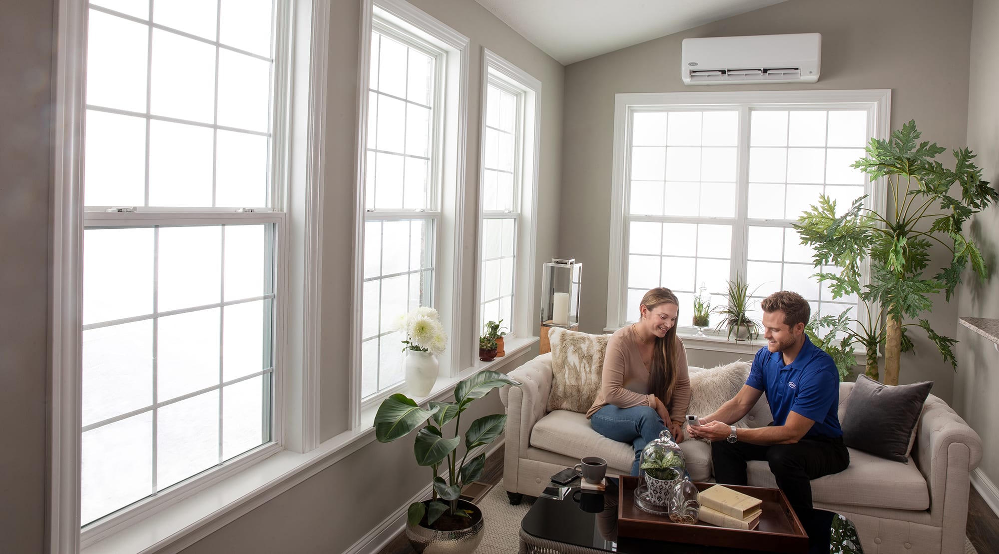 hvac-expert-showing-woman-the-remote-control-after-a-mini-split-repair An HVAC expert showing woman the remote control after a mini split repair.