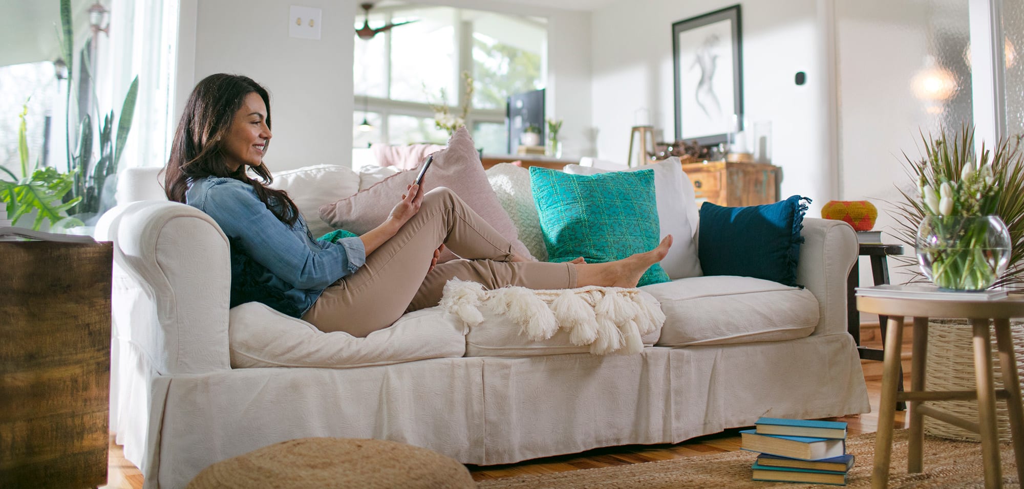 A woman researches Carrier air conditioner cost on her phone while laying on a couch A woman researches Carrier air conditioner cost on her phone while laying on a couch.