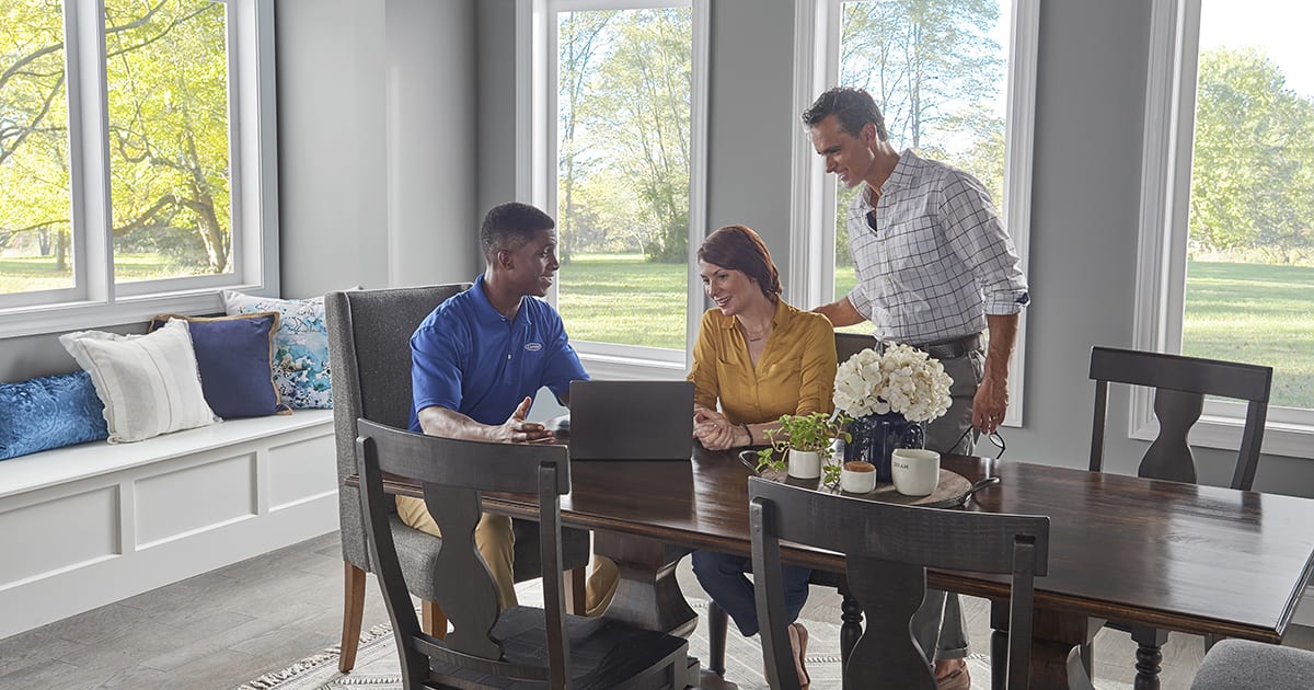 A Carrier dealer sits at a table with a couple to explain what is a smart thermostat. A Carrier dealer sits at a table with a couple to explain what is a smart thermostat.