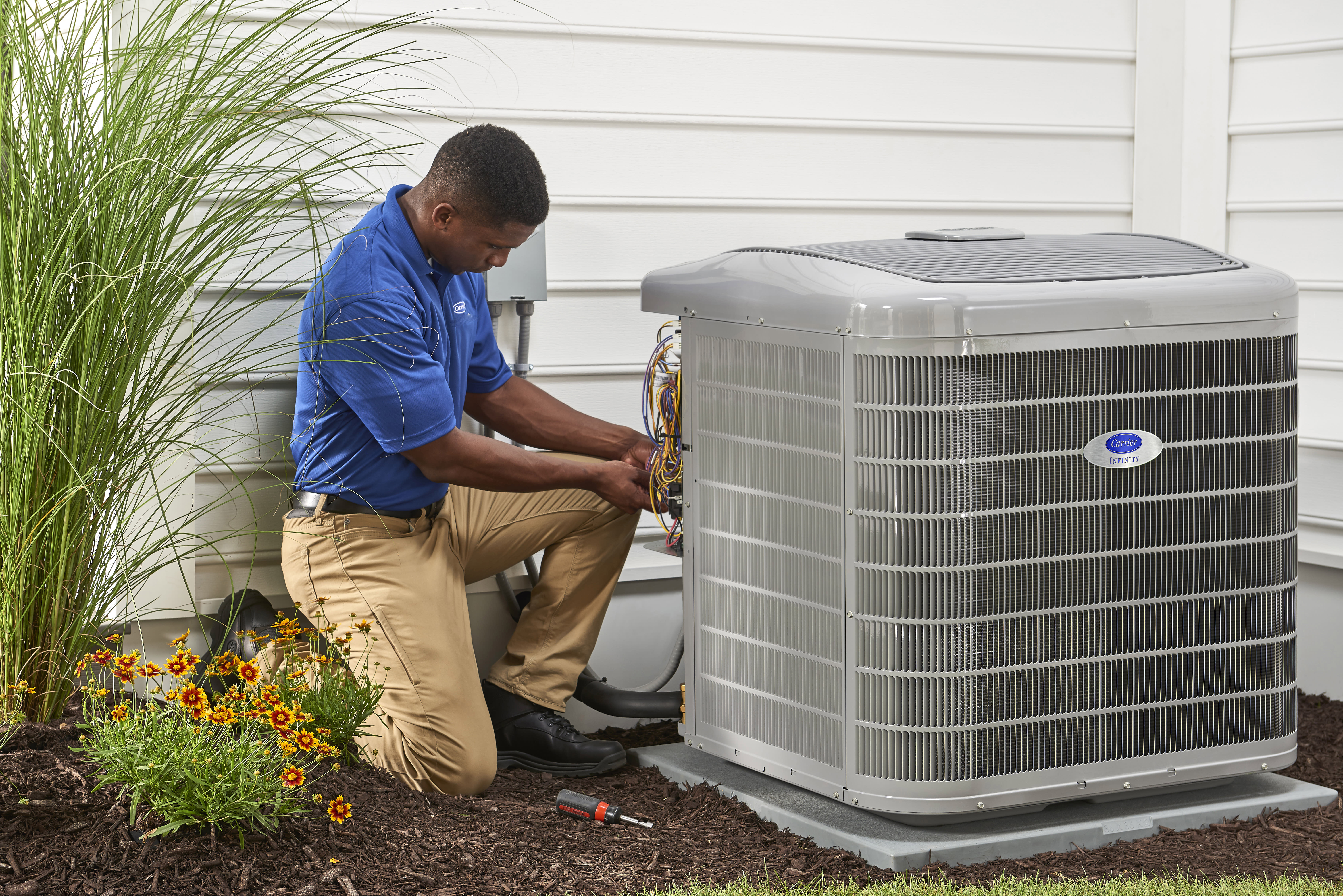 a carrier dealer services an hvac unit outside of a home a carrier dealer services an hvac unit outside of a home