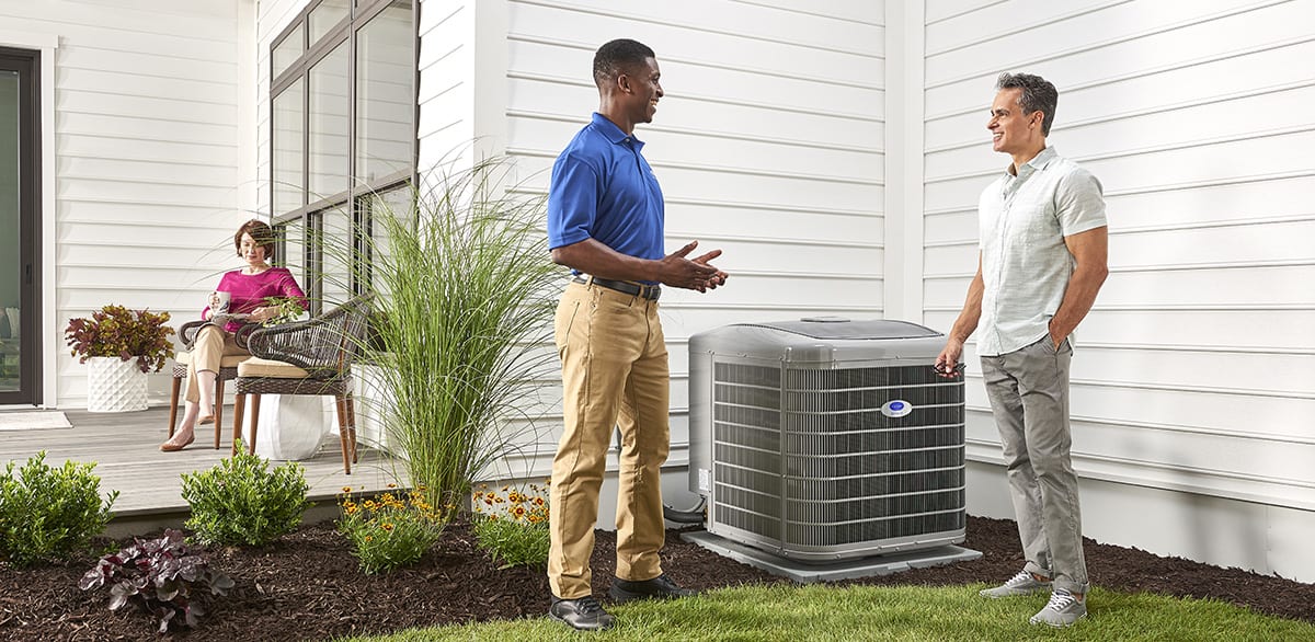 a carrier dealer explains reasons for heat pump not working to man outside home