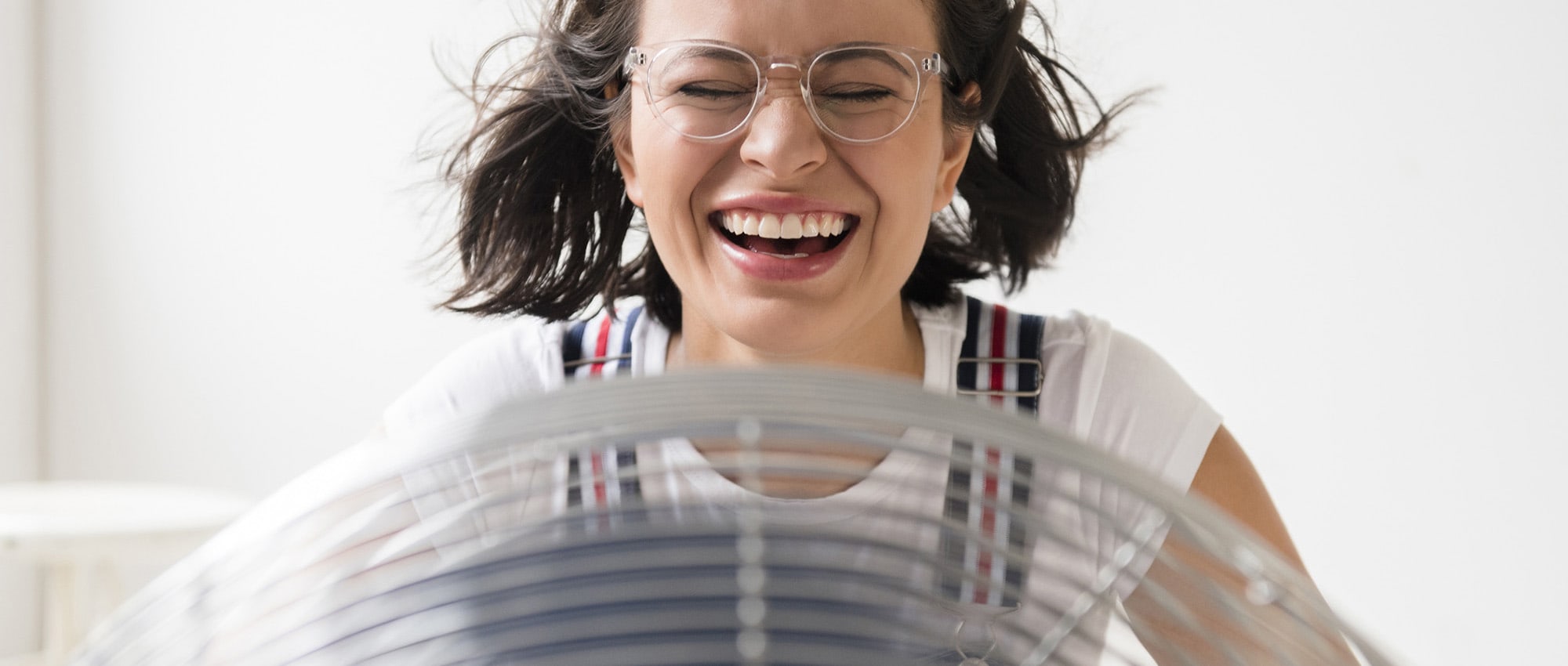 a woman without house ac sits in front of a fan after learning how does air conditioning work in air conditioning systems