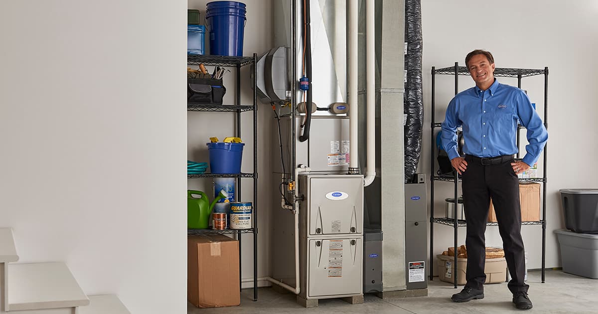 carrier dealer stands next to furnace after performing heating repair carrier dealer stands next to furnace after performing heating repair