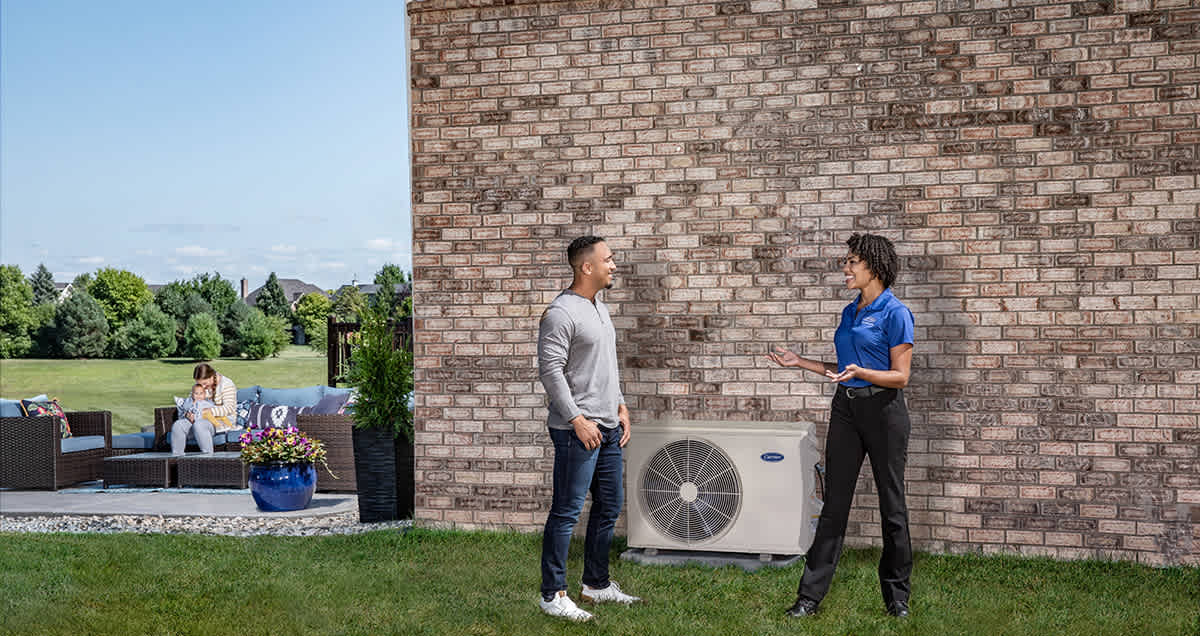a carrier dealer talks to a man by a ductless ac system