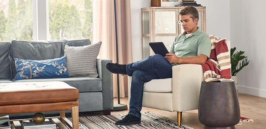 a homeowner researches do air purifiers help with smell on tablet in chair a homeowner researches do air purifiers help with smell on tablet in chair