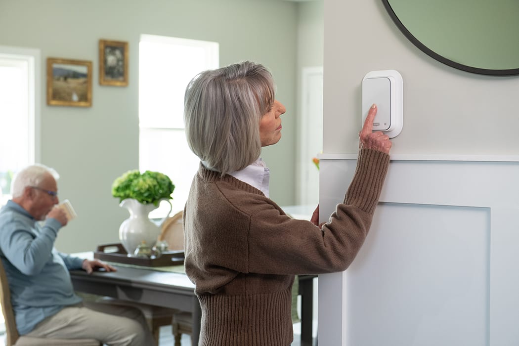 a woman adjusts her heat pump thermostat in the hallway a woman adjusts her heat pump thermostat in the hallway