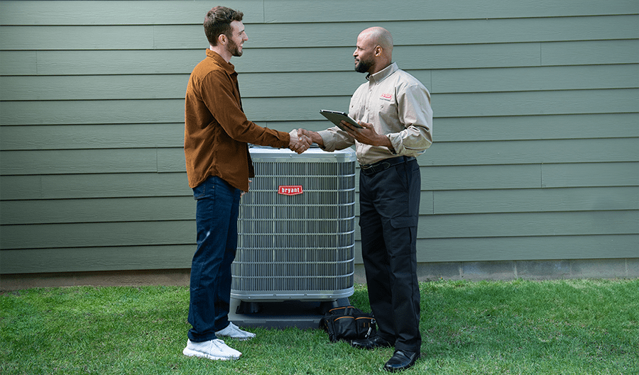 a-bryant-dealer-discusses-heat-pump-benefits-with-homeowner-outside a-bryant-dealer-discusses-heat-pump-benefits-with-homeowner-outside