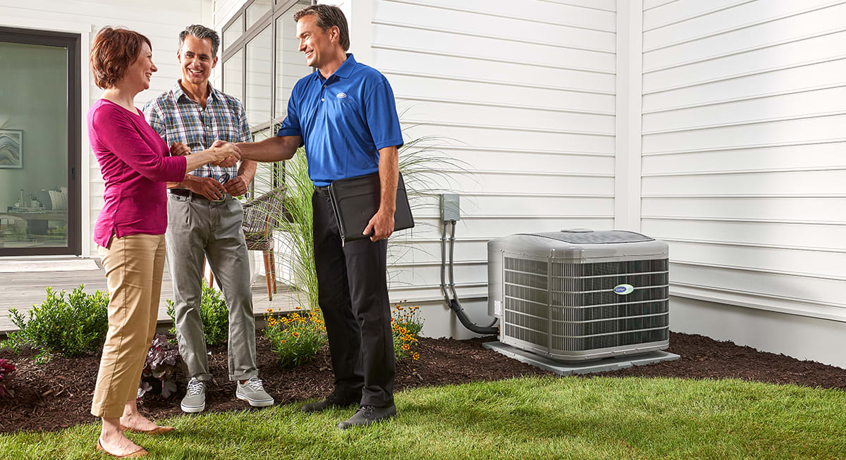 a carrier dealer shakes a homeowner's hand by a 2 ton ac unit a carrier dealer shakes a homeowner's hand by a 2 ton ac unit