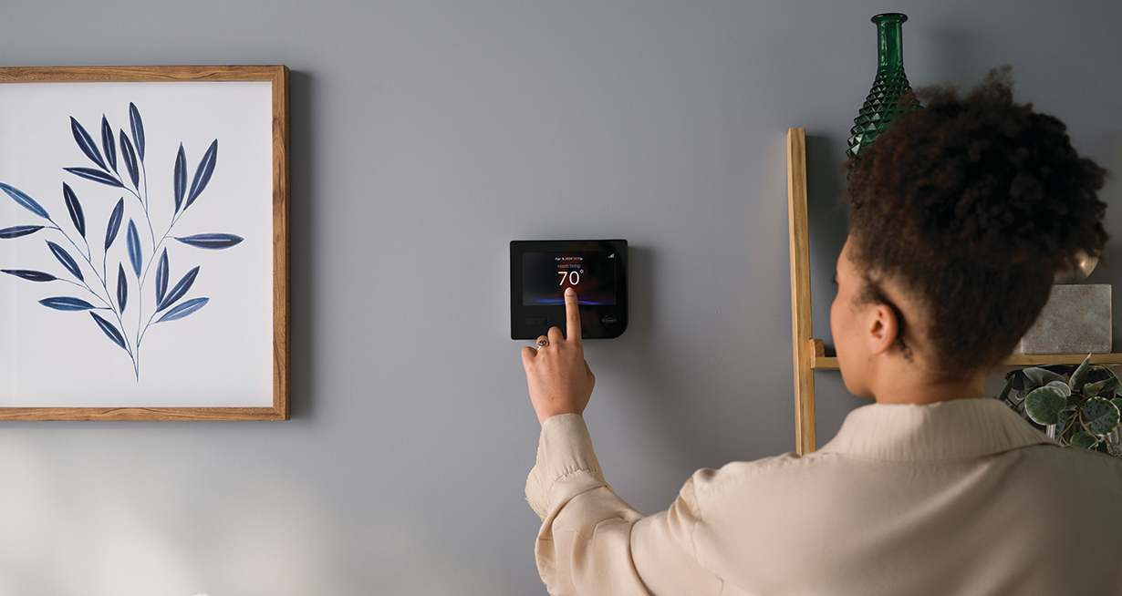 a woman sets the temperature on her carrier thermostat replacement a woman sets the temperature on her carrier thermostat replacement