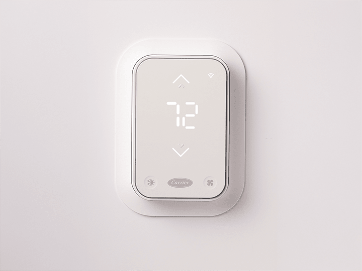A Carrier smart thermostat with InteliSense technology installed on a white wall